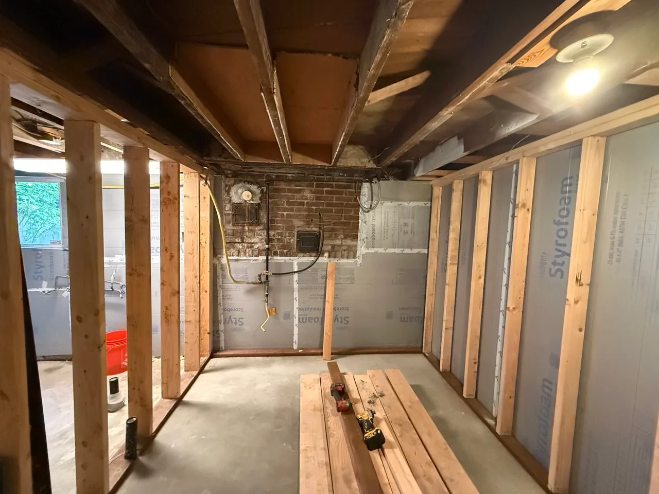Newly framed room beside rigid-foam insulation and an existing brick masonry section
