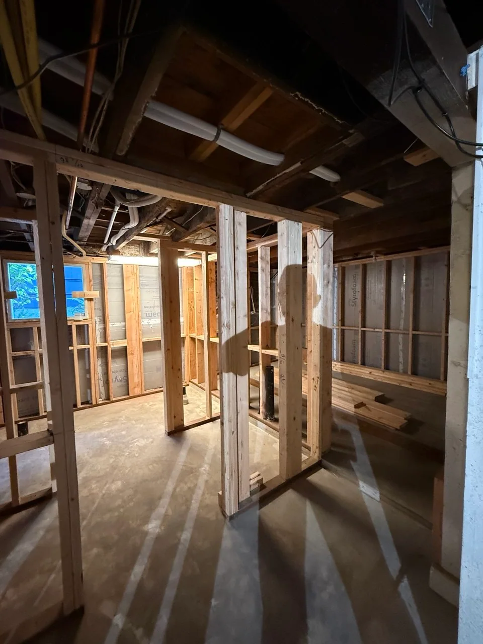 View through completed wall framing with perimeter insulation and staged lumber visible