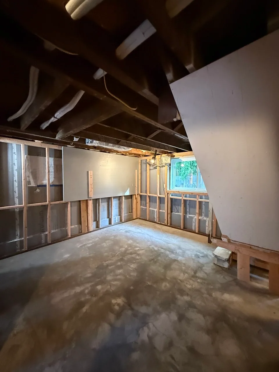 Perimeter room with wall furring, insulation, concrete floor and open ceiling utilities