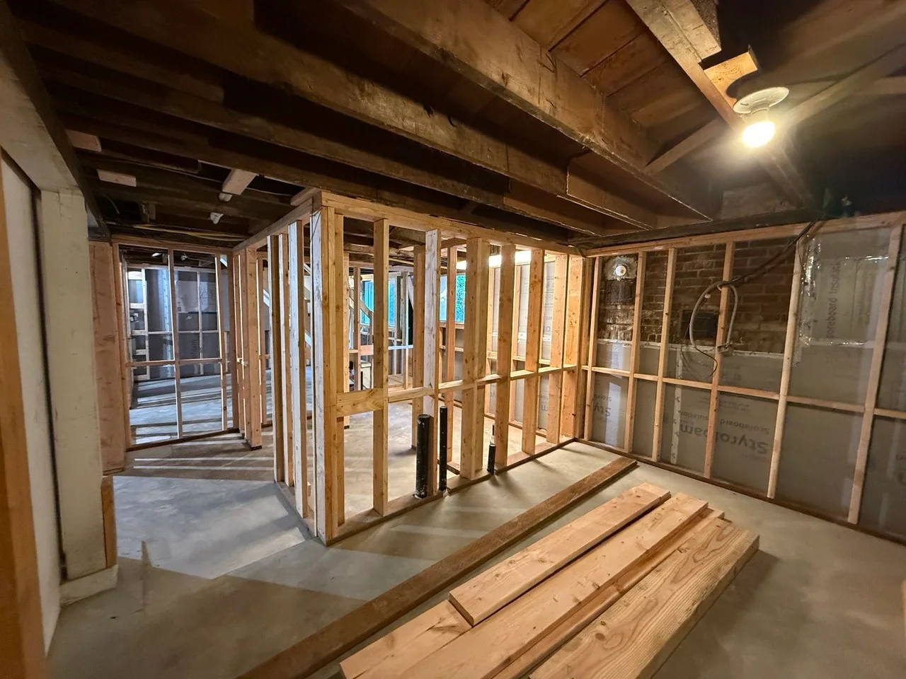 Completed framed room with black plumbing stubs rising through the new concrete floor
