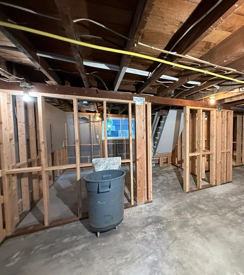 Wide basement view showing completed interior partition framing beneath open ceiling joists
