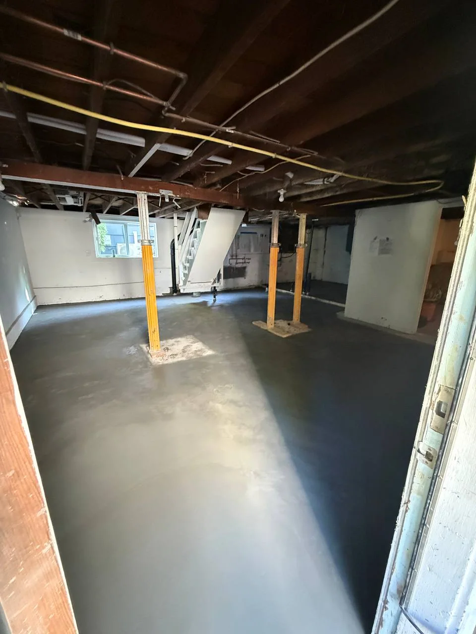 Basement entry view showing the new concrete floor around temporary support posts