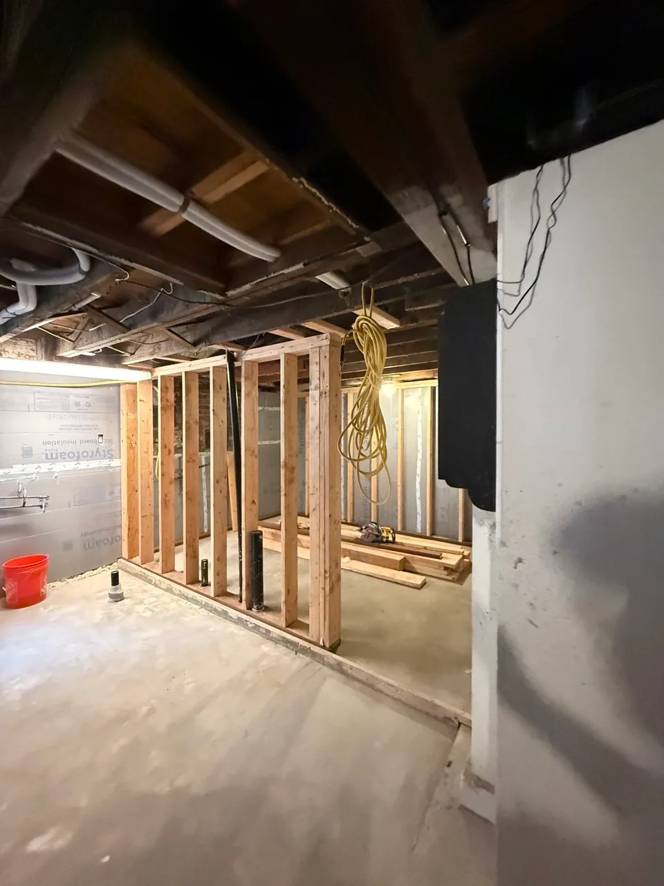 New basement partition framing forming a corridor beside an insulated foundation wall