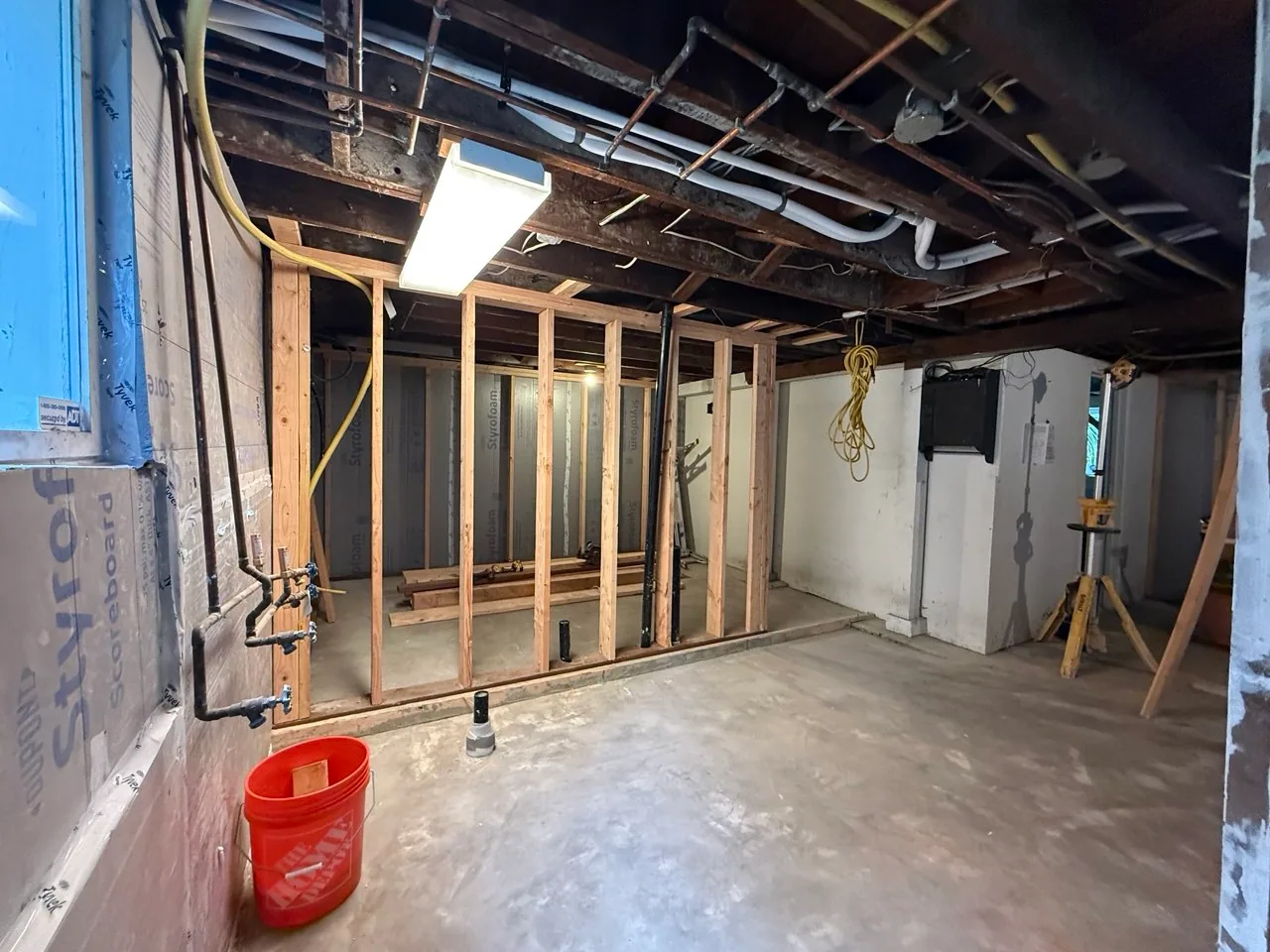 New partition-wall framing arranged around black plumbing stubs in the concrete floor