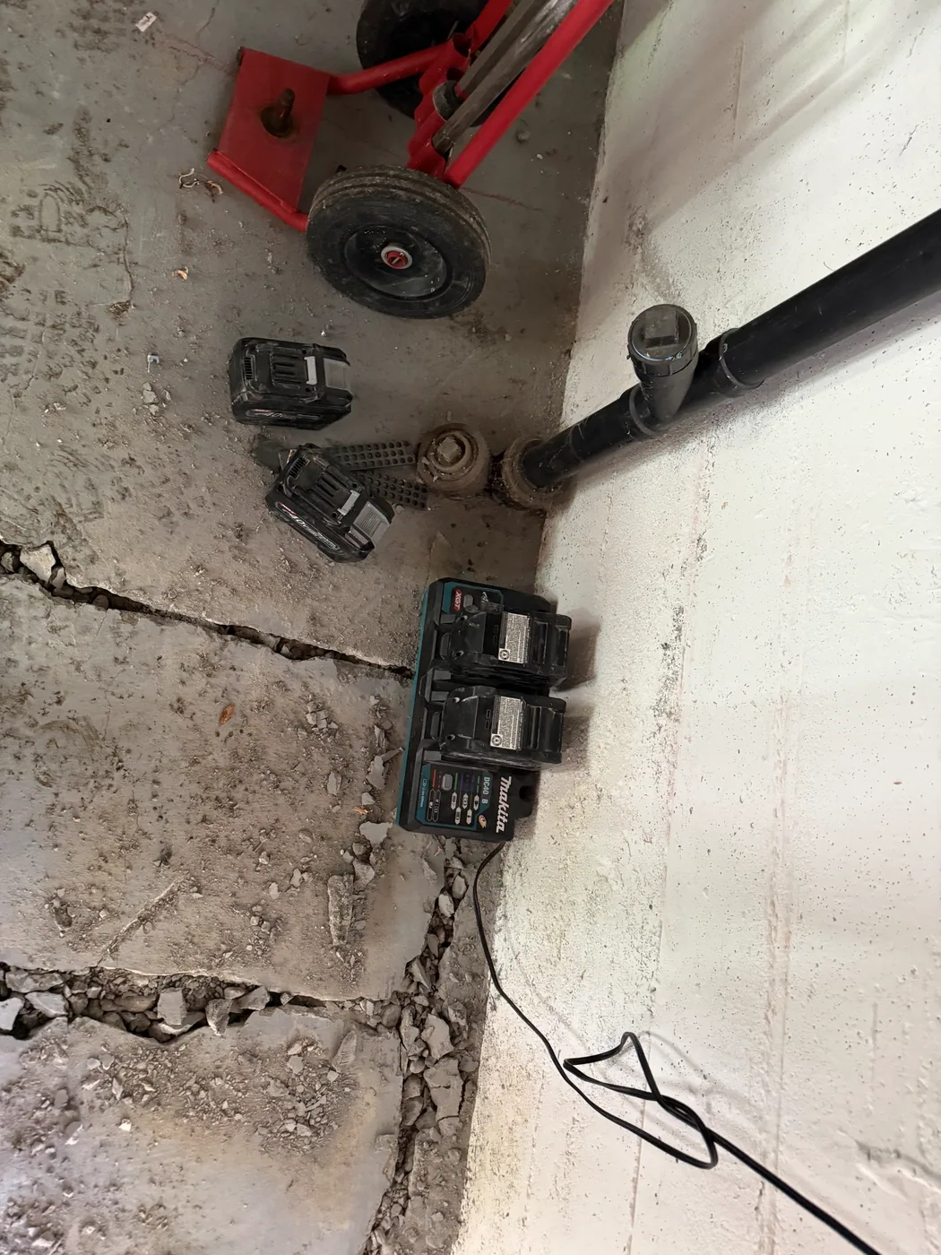 Cut lines in the concrete beside cordless-tool batteries and a hand truck