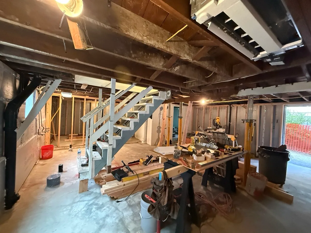 Insulated basement perimeter behind temporary supports, exposed utilities and new framing