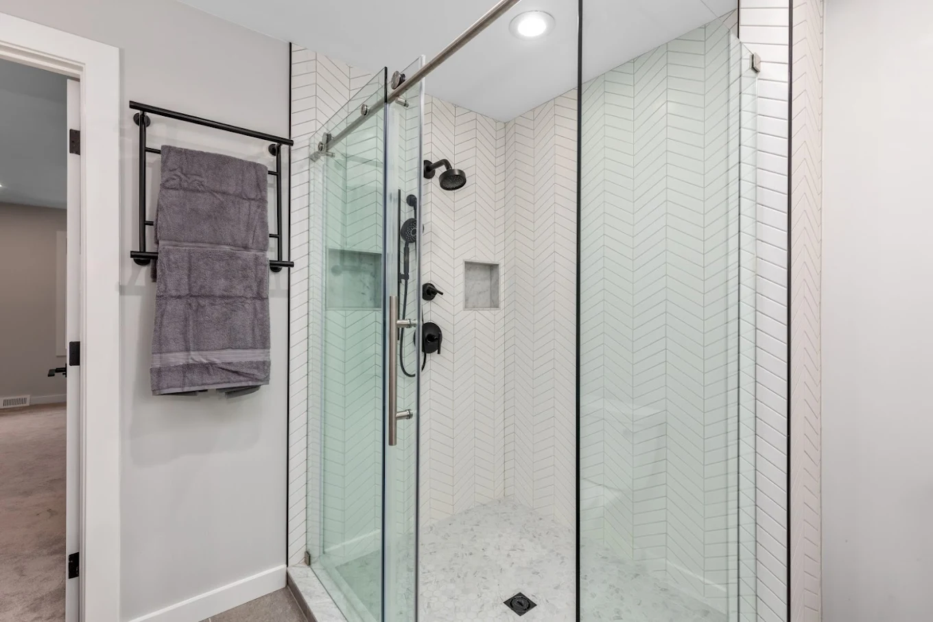 Frameless glass shower with white herringbone tile